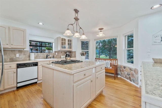 kitchen featuring dishwasher, stainless steel gas cooktop, light wood-type flooring, backsplash, and a kitchen island