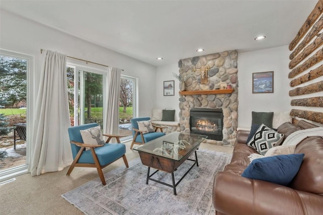 carpeted living room with recessed lighting, a stone fireplace, and visible vents
