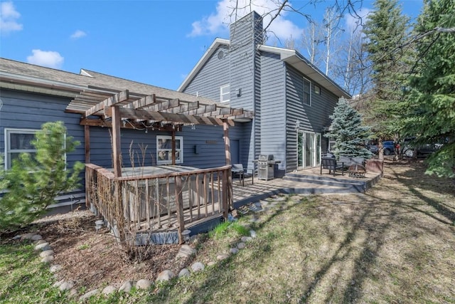 back of property with a patio area, a wooden deck, a pergola, and a chimney
