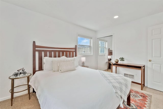 bedroom featuring visible vents, baseboards, a closet, and light carpet