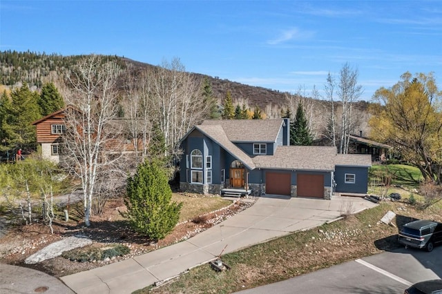 view of front of home featuring a chimney, a garage, a mountain view, and stone siding