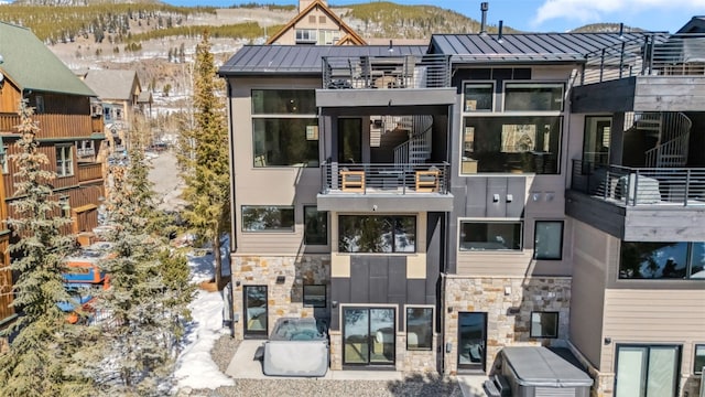 exterior space with a balcony, a standing seam roof, stone siding, a mountain view, and metal roof
