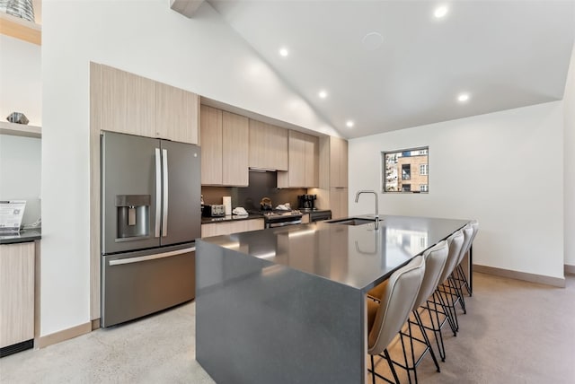 kitchen featuring stainless steel appliances, a sink, dark countertops, recessed lighting, and light brown cabinets