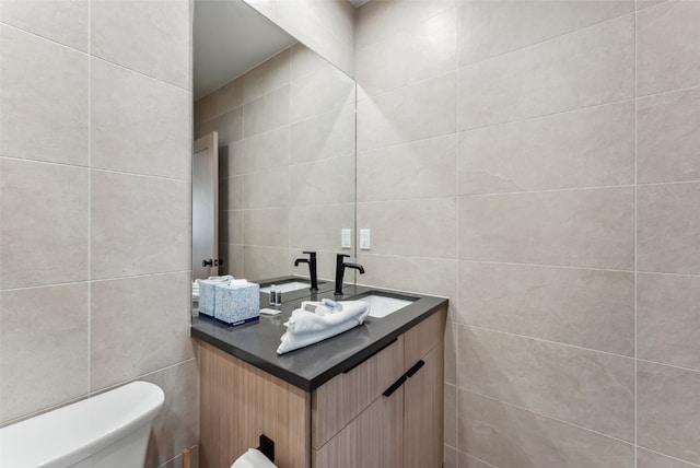 bathroom featuring toilet, vanity, and tile walls