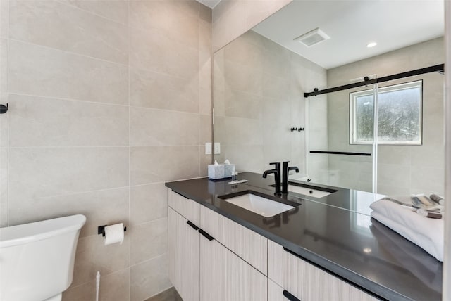 bathroom featuring toilet, vanity, and tile walls