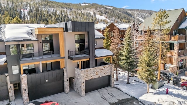 snow covered property featuring an attached garage, driveway, and a mountain view