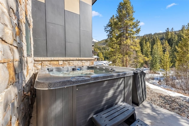 view of patio featuring a forest view and a hot tub