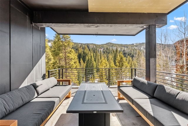exterior space with an outdoor hangout area, a forest view, and a balcony