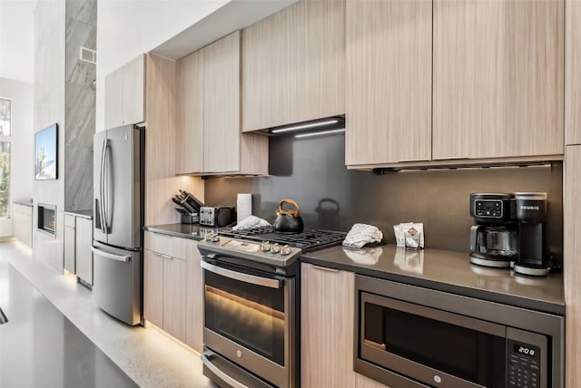 kitchen featuring modern cabinets, wall chimney exhaust hood, appliances with stainless steel finishes, and light brown cabinetry