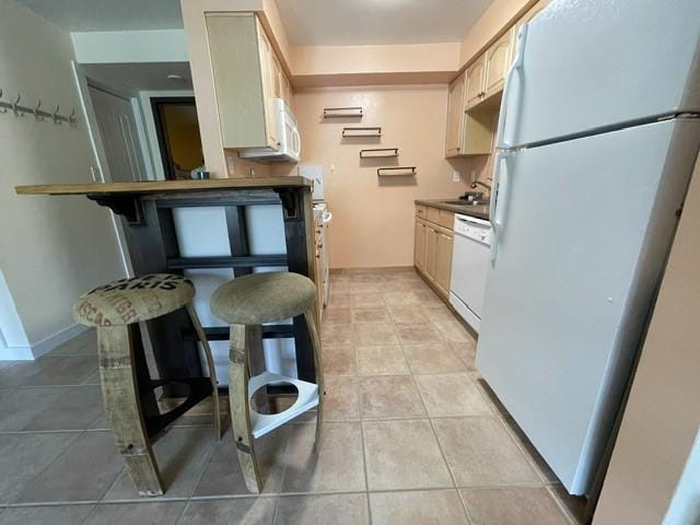 kitchen with light tile patterned floors, white appliances, and a sink