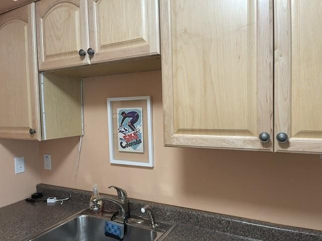 interior details with dark countertops, a sink, and light brown cabinets