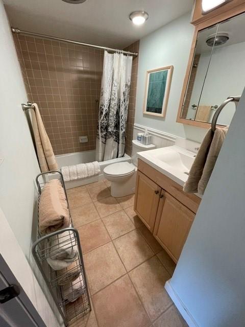 full bath with shower / bath combo, toilet, tile patterned flooring, and vanity