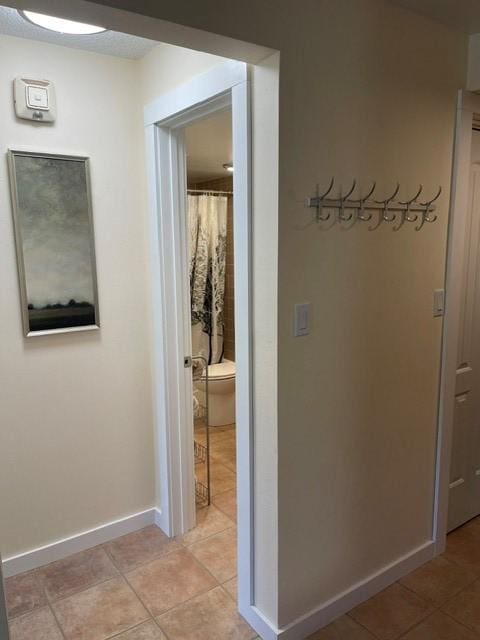 corridor featuring baseboards and light tile patterned floors