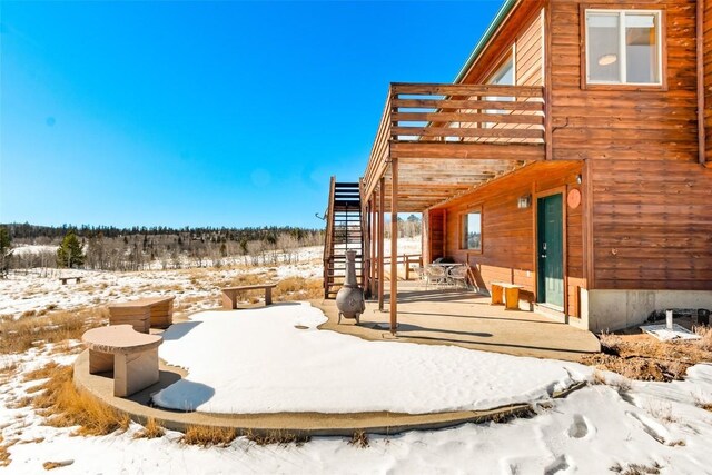 snow covered patio with a wooden deck and stairs