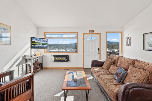 living room featuring a glass covered fireplace, carpet floors, a wealth of natural light, and baseboards