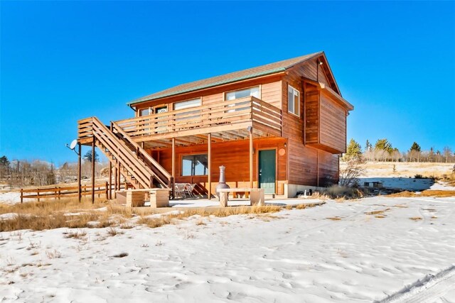snow covered house featuring a deck