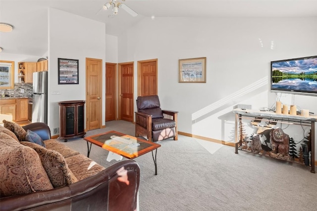 living area with ceiling fan, baseboards, high vaulted ceiling, and light colored carpet