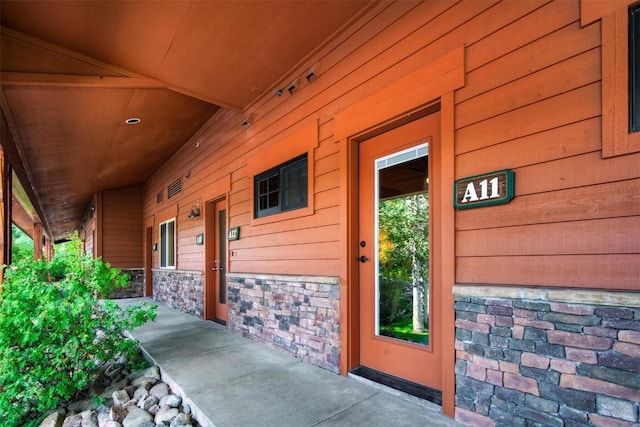 entrance to property featuring a porch and stone siding