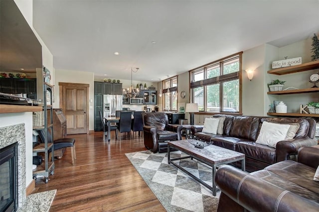 living room with a fireplace with flush hearth, dark wood-type flooring, and a chandelier