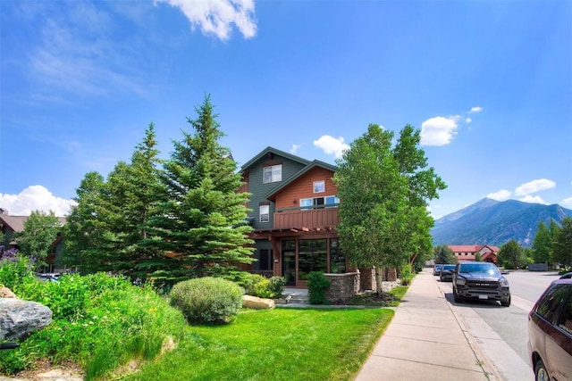 exterior space featuring stone siding, a yard, and a mountain view