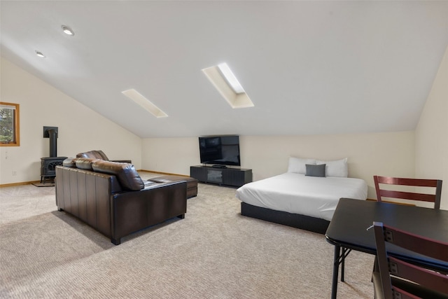 bedroom with light carpet, a wood stove, and lofted ceiling with skylight