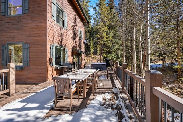 wooden deck with outdoor dining area, a hot tub, and a grill