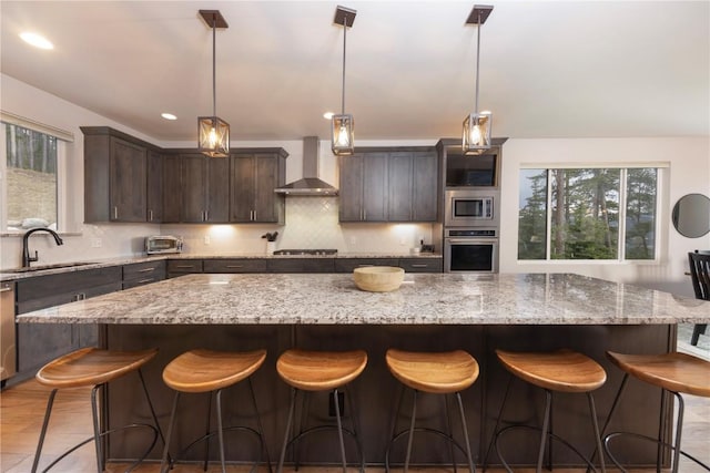 260 N Fuller Placer Rd, Breckenridge, CO 80424 - kitchen featuring wall chimney exhaust hood, appliances with stainless steel finishes, a large island, dark brown cabinetry, and decorative backsplash