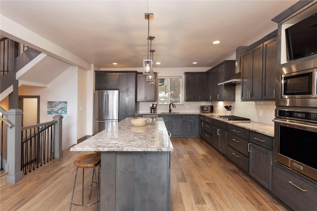 260 N Fuller Placer Rd, Breckenridge, CO 80424 - kitchen featuring stainless steel appliances, wall chimney exhaust hood, a breakfast bar, dark brown cabinetry, and tasteful backsplash