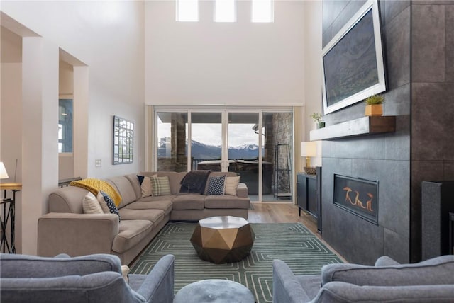 260 N Fuller Placer Rd, Breckenridge, CO 80424 - living area with light wood-style flooring, a high ceiling, a tile fireplace, plenty of natural light, and a mountain view