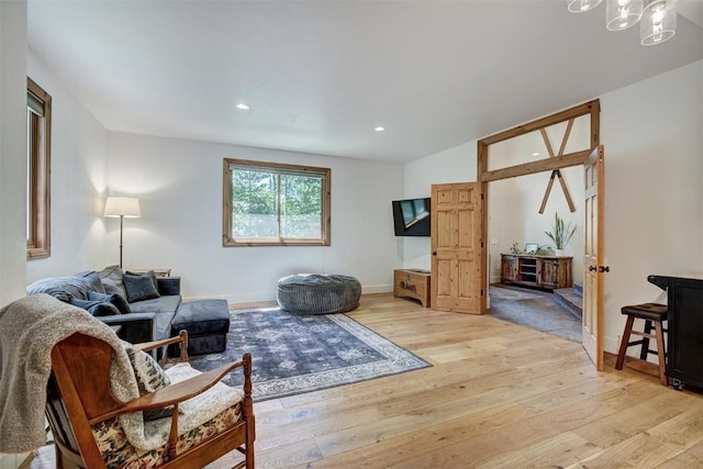 living area with light wood-type flooring, an inviting chandelier, baseboards, and recessed lighting