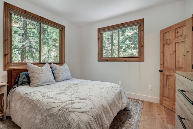 bedroom featuring baseboards, multiple windows, and light wood finished floors