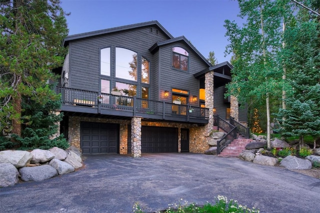 view of front of property featuring stone siding, driveway, stairway, and a garage