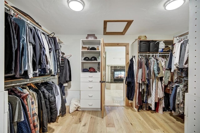 walk in closet with attic access and wood finished floors