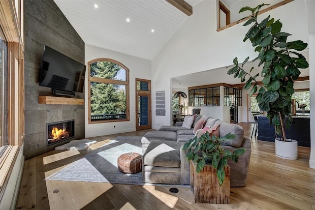 living room with recessed lighting, high vaulted ceiling, beam ceiling, hardwood / wood-style flooring, and a large fireplace