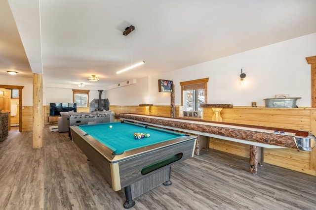 game room featuring wainscoting, wood finished floors, pool table, and a wood stove