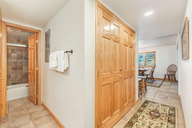 corridor featuring baseboards and light tile patterned floors