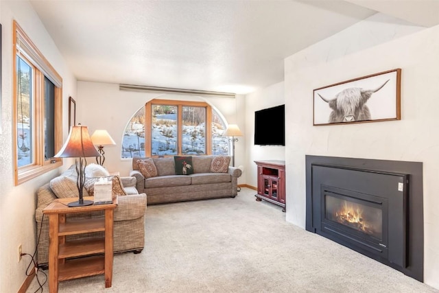 carpeted living room featuring baseboards and a glass covered fireplace