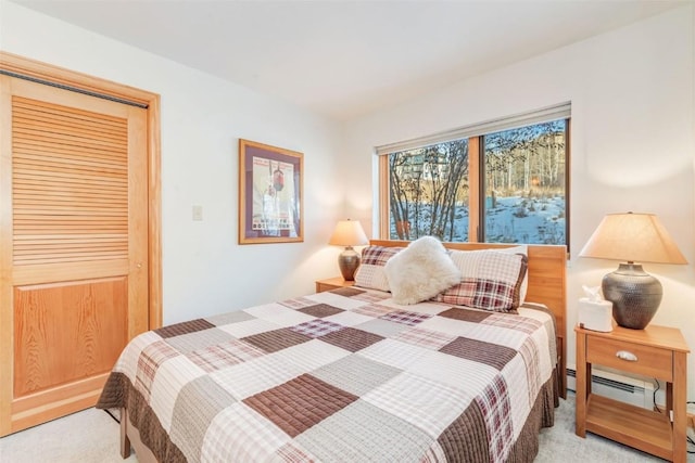 bedroom with a closet, light colored carpet, and baseboard heating