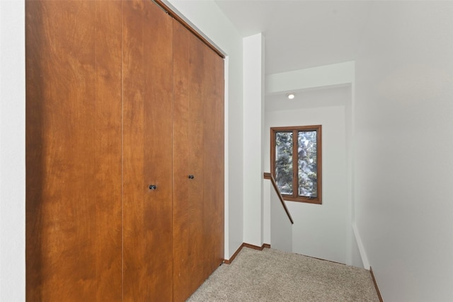 hallway featuring carpet flooring, an upstairs landing, and baseboards