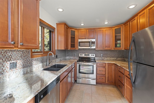 kitchen with stainless steel appliances, a sink, brown cabinets, light tile patterned floors, and recessed lighting
