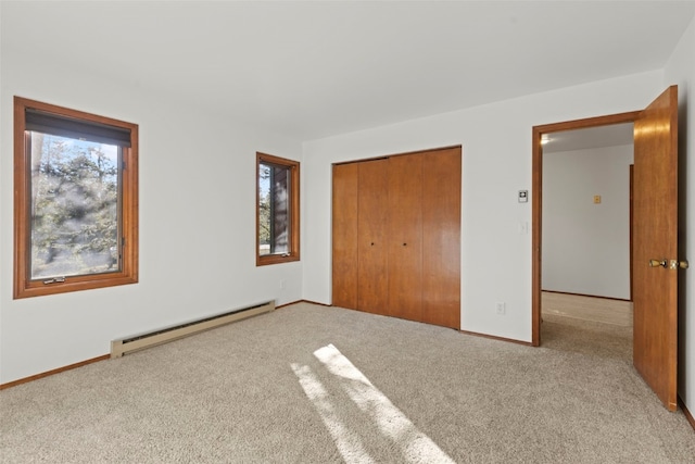 unfurnished bedroom featuring a baseboard heating unit, carpet flooring, a closet, and baseboards