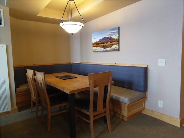 dining room featuring baseboards, carpet floors, and a raised ceiling