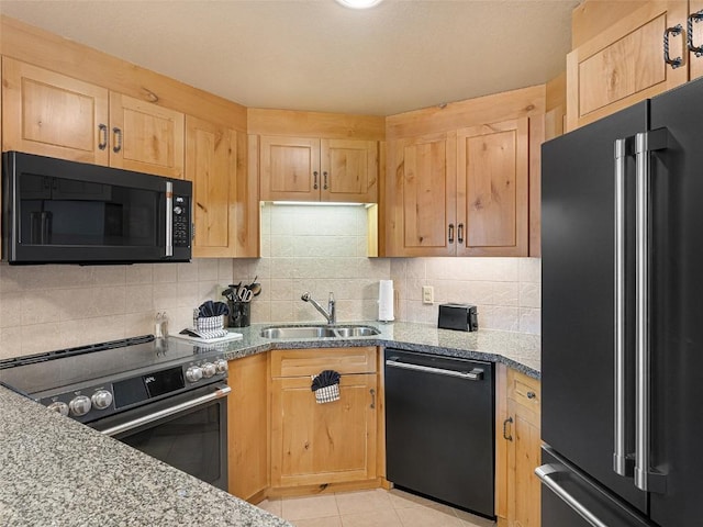 kitchen with light stone counters, black appliances, light brown cabinetry, and a sink