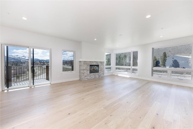 35 Argentine Ct Unit 305, Keystone, CO 80435 - unfurnished living room with light wood-type flooring, a stone fireplace, and recessed lighting