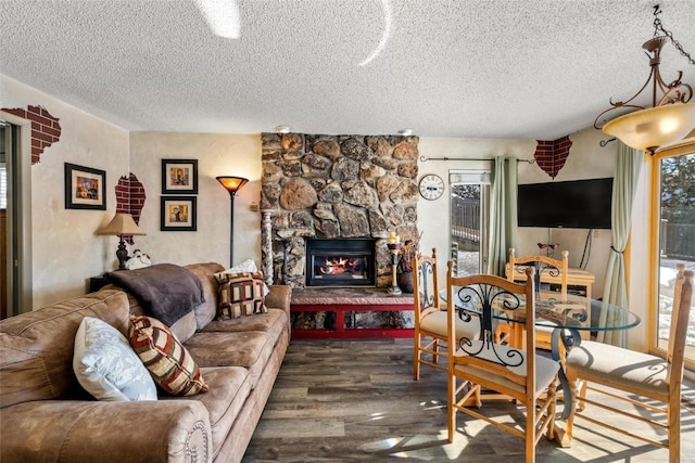 living area with a stone fireplace, wood finished floors, and a textured ceiling
