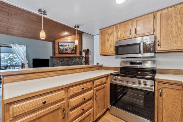 kitchen featuring light countertops, light wood-style floors, decorative light fixtures, a peninsula, and appliances with stainless steel finishes