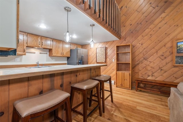 2915 Chinook Ln Unit B22, Steamboat Springs, CO 80487 - kitchen with stainless steel fridge, a breakfast bar area, light wood-style flooring, a sink, and light countertops