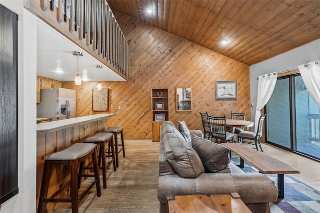 living area featuring wood ceiling, wooden walls, a towering ceiling, and light wood finished floors
