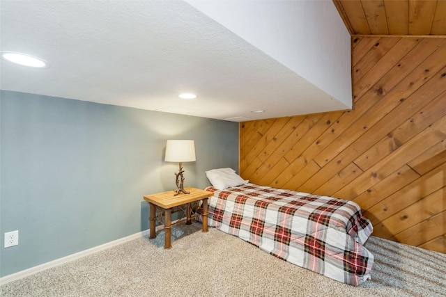 carpeted bedroom with baseboards, wooden walls, and recessed lighting