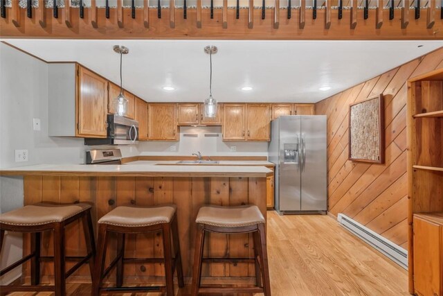 2915 Chinook Ln Unit B22, Steamboat Springs, CO 80487 - kitchen featuring stainless steel appliances, a baseboard radiator, light wood-style floors, a sink, and a peninsula